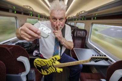 Robb-Weir-onboard-LNER-train-with-guitar-calling-for-quiet-scaled.jpg